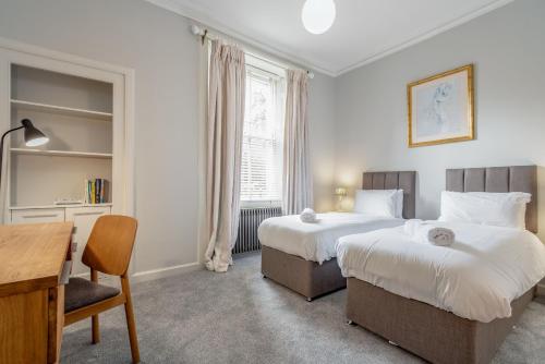 um quarto de hotel com duas camas, uma secretária e uma mesa em Luxury St Andrews Apartment - 5 mins to Old Course em St. Andrews