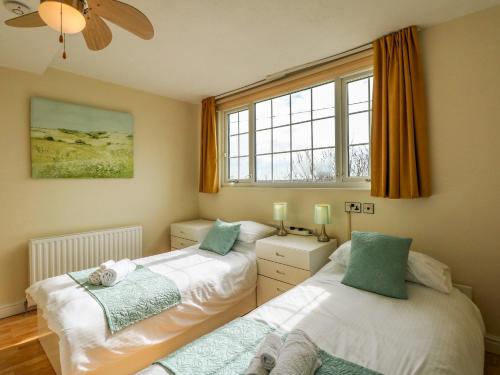 two beds in a room with two windows at Martell Cottage in Skegness