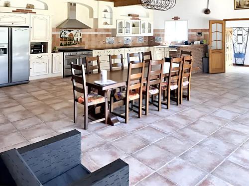 une cuisine avec des armoires blanches et une table et des chaises dans l'établissement Villa spacieuse à Laroque-des-Albères avec piscine privée, à Laroque-des-Albères