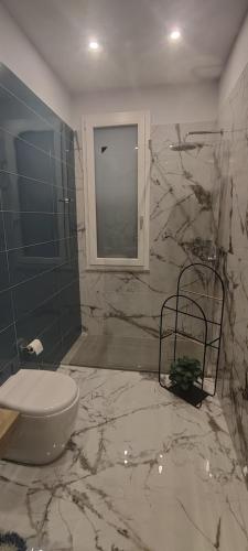 a marble bathroom with a toilet and a window at Crocco D'Oro in Caltavuturo