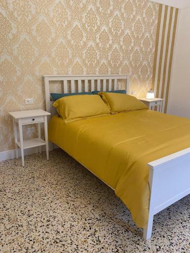 a bedroom with a bed with a yellow bedspread and two tables at La Casa sulla Penisola Sorrentina in Vico Equense