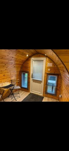 a room with a door and two windows in a wooden wall at New hotub glamping pods in Kinlet