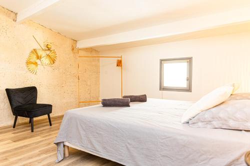 a bedroom with a large bed and a black chair at Mon voisin Van Gogh in Arles