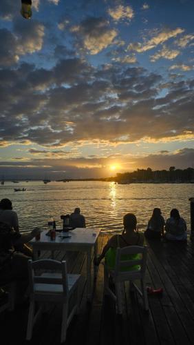 Eine Gruppe von Menschen, die auf einem Dock sitzen und den Sonnenuntergang beobachten. in der Unterkunft Hotel Blue Olas in Bocas del Toro