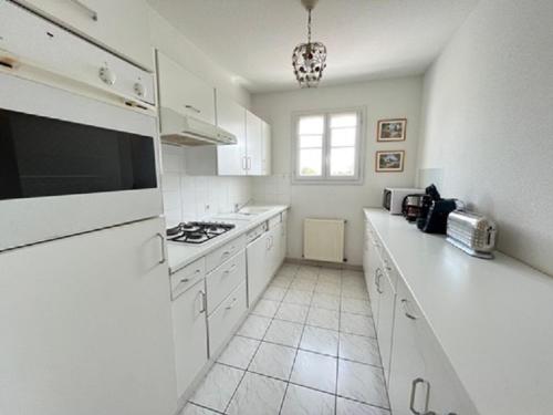 une cuisine avec des placards blancs et un comptoir blanc dans l'établissement Appartement la Capitainerie, à Saint-Gilles-Croix-de-Vie