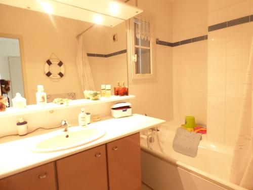 une salle de bain avec un lavabo, un miroir et une baignoire dans l'établissement Appartement la Capitainerie, à Saint-Gilles-Croix-de-Vie
