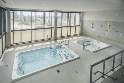 eine große Badewanne in einem großen Zimmer mit Fenstern in der Unterkunft Upscale 1BR Condo with King Bed and Amazing Cityscape Views in Kitchener