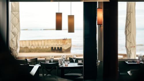 a dining room with a view of the ocean at Hôtel De La Marine in Arromanches-les-Bains
