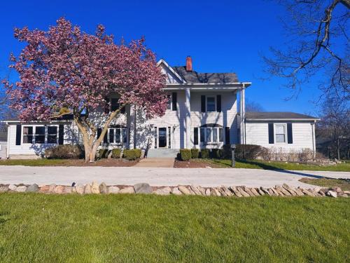 a white house with a tree in front of it at Speedway Legacy Inn in Indianapolis