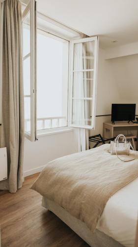 a bedroom with a bed and a large window at Hôtel De La Marine in Arromanches-les-Bains