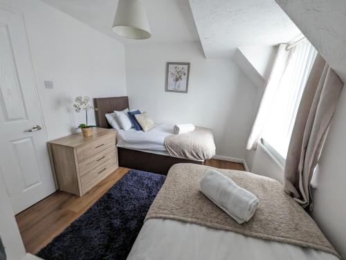 a bedroom with two beds and a dresser and a window at Dean House, 2 BR, Sleeps 5,Kitchen, FREE Parking, Spacious, Garden, Close Motorways in Doncaster