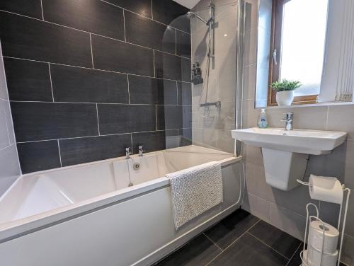 La salle de bains est pourvue d'une baignoire et d'un lavabo. dans l'établissement Dean House, 2 BR, Sleeps 5,Kitchen, FREE Parking, Spacious, Garden, Close Motorways, à Doncaster