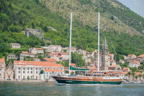 a boat sitting in the water in front of a city at Traditional Sailing Yacht in Tivat
