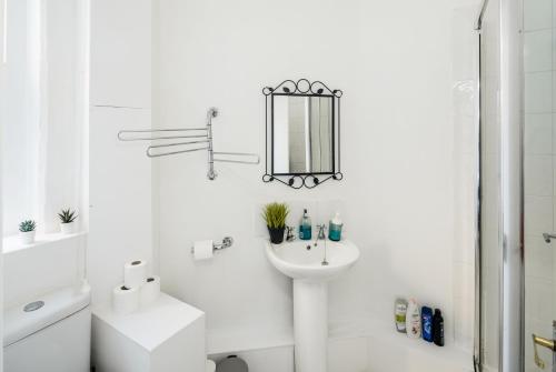 a white bathroom with a sink and a mirror at Cosy 1 bedroom home in Fitzrovia in London