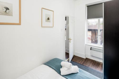 a white bedroom with a bed and a window at Cosy 1 bedroom home in Fitzrovia in London