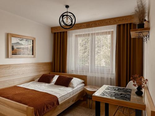 um quarto com uma cama, uma mesa e uma janela em Willa Bliźniaczek em Zakopane