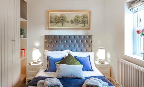 a bedroom with a bed with blue and white pillows at Honey Pot, Chipping Campden, parking, garden, late check-out in Chipping Campden