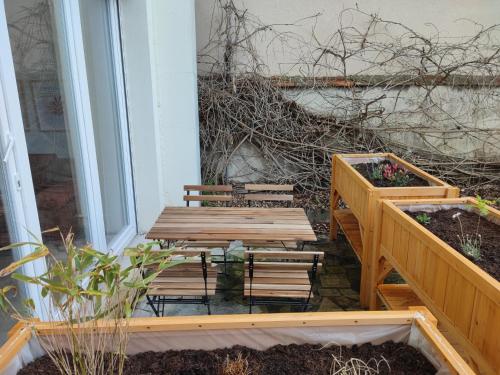 a patio with two benches and a table with plants at Appartement d'architecte avec vue sur jardin in La Courneuve
