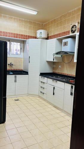 cocina con armarios blancos y suelo de baldosa en فيلا السلطان villa alsoltan en Al Ula