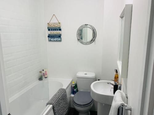 a white bathroom with a toilet and a sink at Captain's Keep - Brixham in Brixham