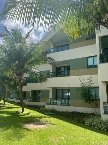 un edificio con una palmera delante de él en Carneiros Beach Resort - Flat 111-D en Praia dos Carneiros