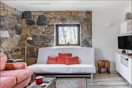 a living room with a white couch and a stone wall at Studio Guest Suite in Forest Cottage in Tryon