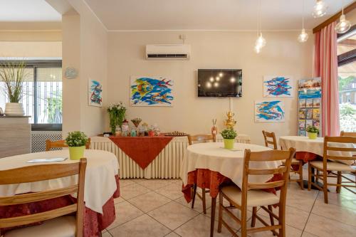 a restaurant with tables and chairs and a tv at Hotel Stella Del Mare in Cervia