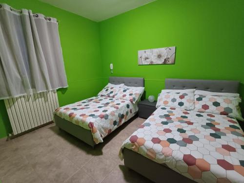 a bedroom with two beds and green walls at Sotto Li Foj in Picerno