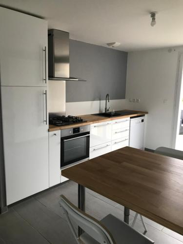 une cuisine avec des armoires blanches et une table en bois dans l'établissement Villa les hortensias, à Vaucelles