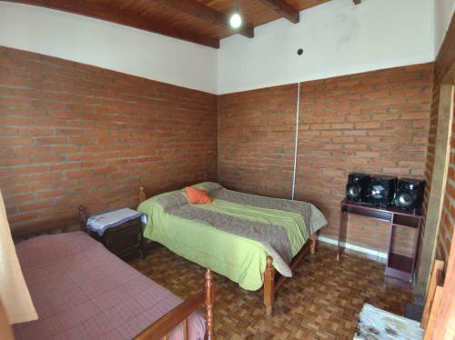 um quarto com uma cama e uma parede de tijolos em Hospedaje Las Dalias em San José