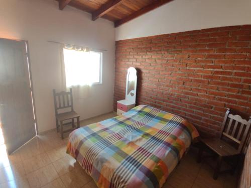 sypialnia z łóżkiem i ceglaną ścianą w obiekcie Hospedaje Las Dalias w mieście San José