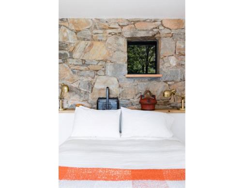Ce lit se trouve dans un dortoir doté d'un mur en pierre. dans l'établissement Studio Guest Suite in Forest Cottage, à Tryon