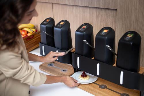 a woman standing at a counter with a plate of food at Moov Hotel Porto Norte in Porto