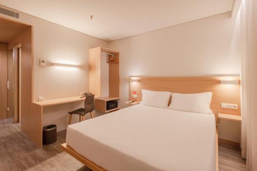 a bedroom with a large white bed and a desk at Moov Hotel Porto Norte in Porto