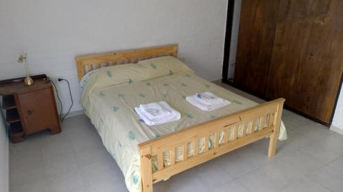 een slaapkamer met een houten bed en handdoeken bij Av Edison - El departamento de Lis in Santa Rosa