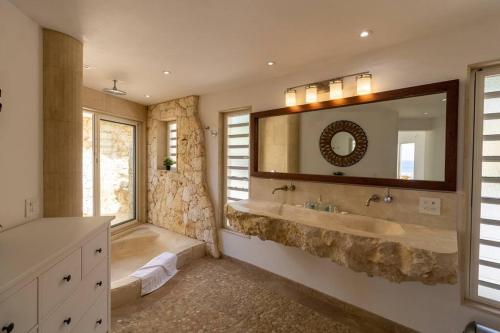 een badkamer met een grote wastafel en een grote spiegel bij Pelikaan Sunset:A Villa With Stunning Ocean Views in Koolbaai