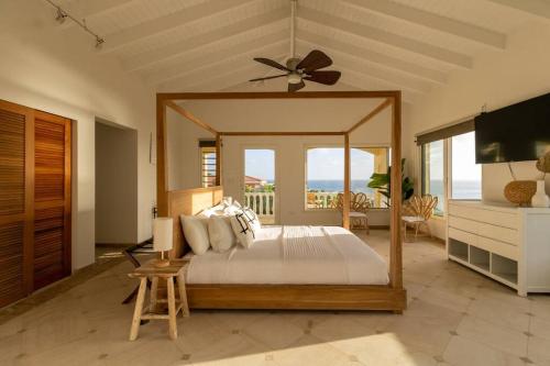 een slaapkamer met een hemelbed en uitzicht op de oceaan bij Pelikaan Sunset:A Villa With Stunning Ocean Views in Koolbaai