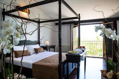 希克利的住宿－Zeta Resort Donnalucata，一间带四柱床的卧室和一个阳台