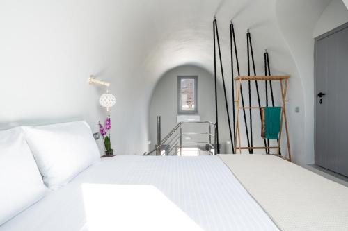 a white bedroom with a white bed and a staircase at MelivOia house collection in Foinikiá