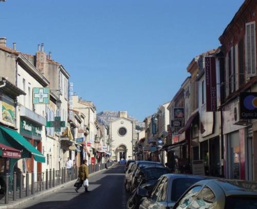 eine Person, die mit Autos eine Stadtstraße entlangläuft in der Unterkunft Magnifique Maison de Village aux abords des Calanques in Marseille