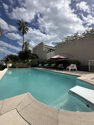une piscine avec de l'eau bleue devant un immeuble dans l'établissement Nice Living Hôtel Particulier Piscine, à Saint-Laurent-du-Var