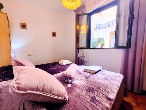 um quarto com uma cama com almofadas e uma janela em El Balcón de Zuheros em Zuheros