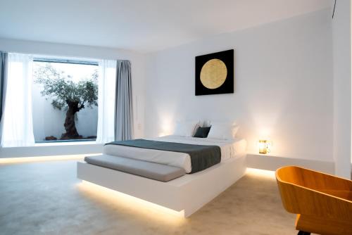 a white bedroom with a bed and a window at Heavens Edge in Imerovigli