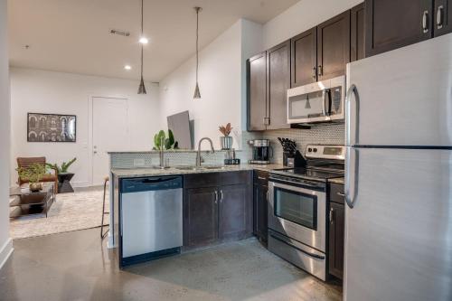 a kitchen with stainless steel appliances and wooden cabinets at Lofts At 30th - Modern Life - Mins To Broadway in Nashville