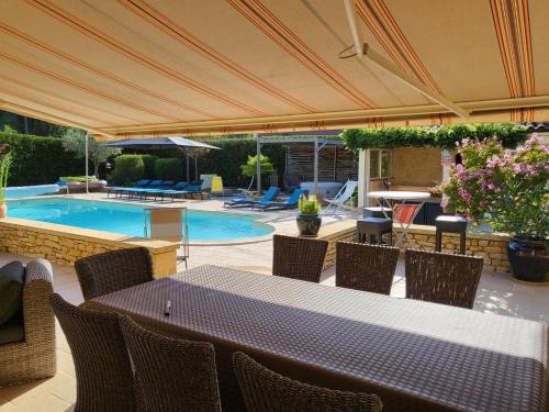 un patio avec une table et des chaises et une piscine dans l'établissement La Grange Sud, à Carsac-Aillac