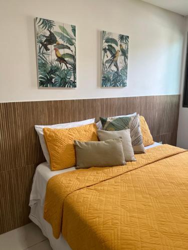 um quarto com uma cama amarela com duas fotografias na parede em Carneiros Beach Resort - Flat 111-D em Praia dos Carneiros