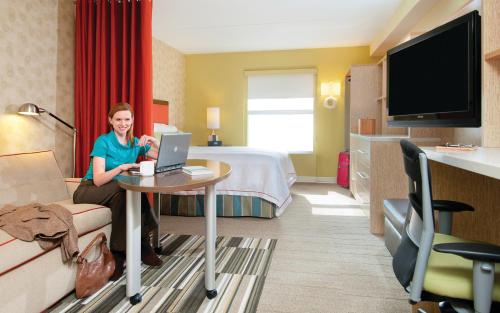 una mujer sentada en una mesa en una habitación de hotel en Home2 Suites By Hilton Austin East Side en Austin
