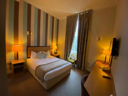 a hotel room with a bed and a television at The Riverside House Hotel in Mildenhall