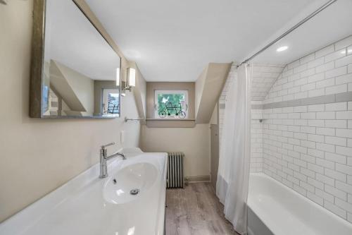 a white bathroom with a tub and a sink at Luxury Loft in Historic Carriage House in Kennett Square