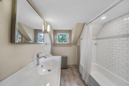 Un baño blanco con bañera y lavabo. en Luxury Loft in Historic Carriage House, en Kennett Square